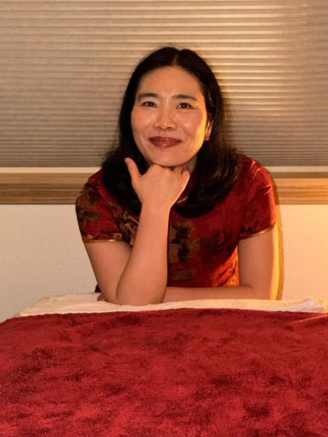 Lily, licensed massage therapist in Portland, Oregon, smiling beside her treatment table